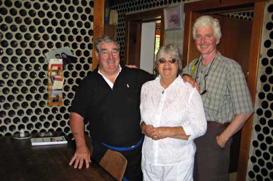 Bob and Heather Tofts and Pat Keough in their kitchen, beer bottle walls